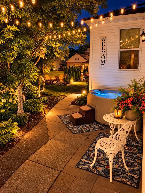 Un espacio exterior bien iluminado con un jacuzzi, asientos y un letrero de bienvenida.