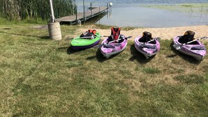 Une zone herbeuse au bord du lac, avec des kayaks et un quai.
