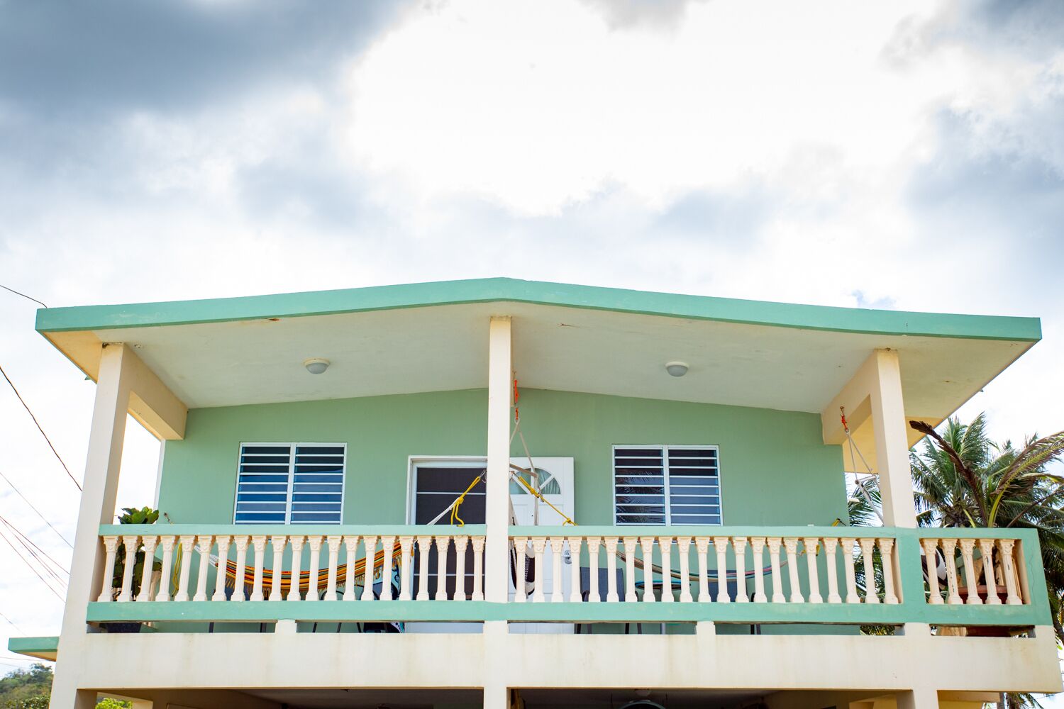 A two-story building with a balcony, a flat roof, and a small window on the second floor.