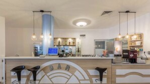 A bar area with a counter, bar stools, and a digital screen. - 1-bed Modern Sea View Apartment in Aparthotel (Pomorie)