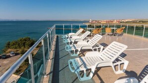 A terrace with white lounge chairs and a glass balustrade overlooking the sea. - 1-bed Modern Sea View Apartment in Aparthotel (Pomorie)