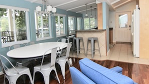 A dining area with a white table and chairs, a blue sofa, and a kitchen area with a refrigerator and bar stools. - JOMO TriTerrace Enjoy Family, Relax Lakefront, Lake View, Priv dock Boat Slip (Rocky Mount)