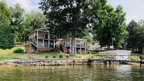 A lakeside property with a multi-story building, a dock, and a stone retaining wall. - JOMO TriTerrace Enjoy Family, Relax Lakefront, Lake View, Priv dock Boat Slip (Rocky Mount)