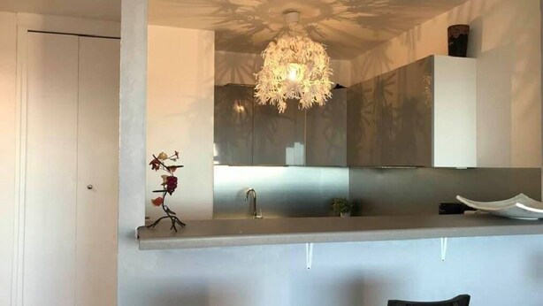 A modern kitchen with a central island, a chandelier, and a white door. - T2 , 50m² Avec vue mer à Carnon Plage (Mauguio)