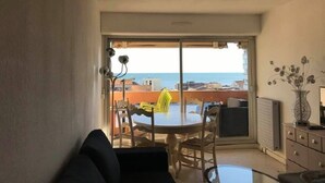 A balcony with a table and chairs, a view of the sea, and a vase with flowers. - T2 , 50m² Avec vue mer à Carnon Plage (Mauguio)