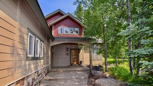 A two-story house with a brick pathway leading to the front door, surrounded by trees and large rocks. - Hart of McCall - Mountain retreat with hot tub and sauna near downtown and golf (McCall)