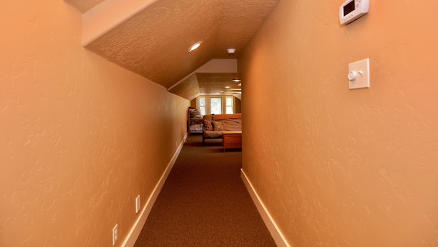 A narrow hallway with a sloped ceiling and a bed at the end. - Hart of McCall - Mountain retreat with hot tub and sauna near downtown and golf (McCall)