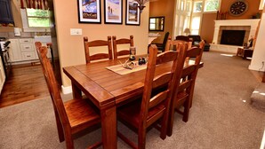 A dining area with a wooden table and chairs, framed pictures on the wall, and a fireplace in the background. - Hart of McCall - Mountain retreat with hot tub and sauna near downtown and golf (McCall)