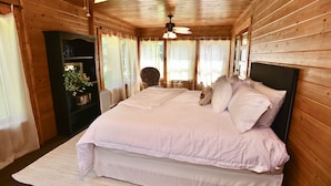 A wooden cabin bedroom with a large bed, a ceiling fan, and a bookshelf. - Hart of McCall - Mountain retreat with hot tub and sauna near downtown and golf (McCall)