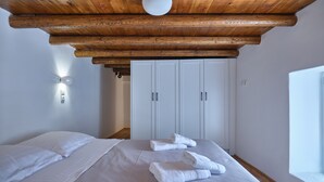 A bedroom with a wooden ceiling, white wardrobe, and a bed with white linens. - Happy Retreat Paros (Paros)