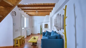 A spacious living room with a wooden ceiling, a blue sofa, a yellow table, and a wooden bench. - Happy Retreat Paros (Paros)