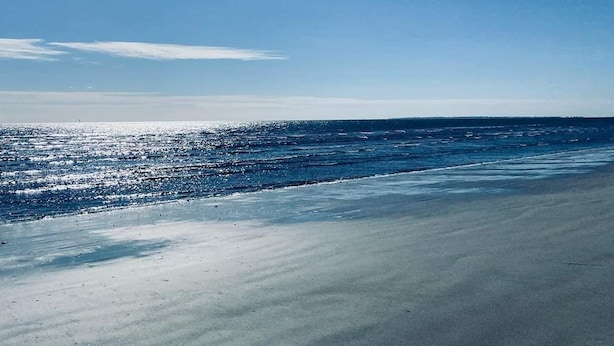 Una playa con cielo despejado y mar tranquilo.