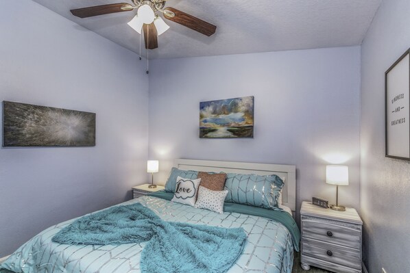 A bedroom with a bed, nightstands, a ceiling fan, and wall art. - Beautiful, spacious, 4 king-beds home with heated and covered pool (Clearwater)