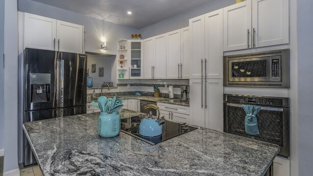 Una cocina moderna con gabinetes blancos, electrodomésticos de acero inoxidable y encimeras de granito.
