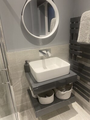 Une salle de bain moderne avec un lavabo rectangulaire blanc, un miroir rond et un porte-serviettes.