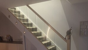 A modern interior with a wooden staircase, a kitchen area, and a dining space.