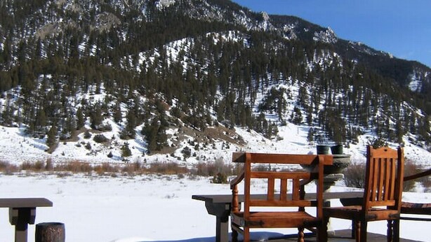 A wooden bench and table set against a snowy mountain backdrop. - Private Island in Big Sky-Great Fishing & Hunting (Big Sky)