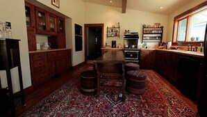 A spacious kitchen with wooden cabinets, a central island, and a patterned rug. - Private Island in Big Sky-Great Fishing & Hunting (Big Sky)