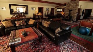 A spacious living room with a large sofa, a coffee table, and a fireplace. - Private Island in Big Sky-Great Fishing & Hunting (Big Sky)