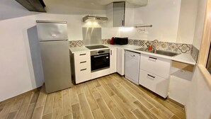 A compact kitchen with a refrigerator, oven, dishwasher, and a small countertop. - At the foot of Mont Ventoux<br>Village center<br>Fully renovated apartment<br> (Malaucène)