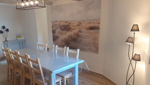A dining area with a long table and chairs, a painting on the wall, and a floor lamp. - At the foot of Mont Ventoux<br>Village center<br>Fully renovated apartment<br> (Malaucène)