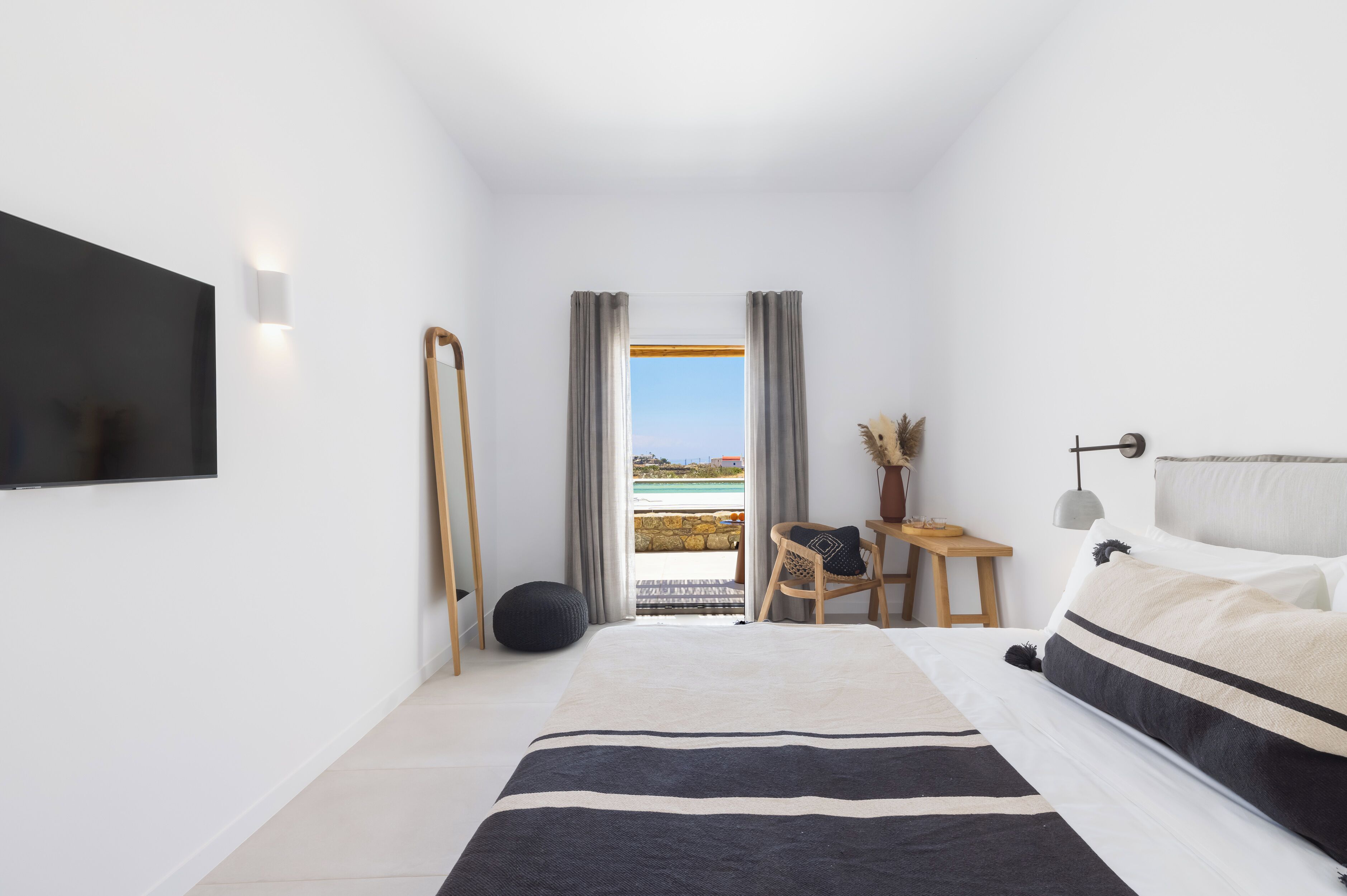 Ein modernes Schlafzimmer mit einem großen Bett, einem Schreibtisch und Blick auf das Meer.
