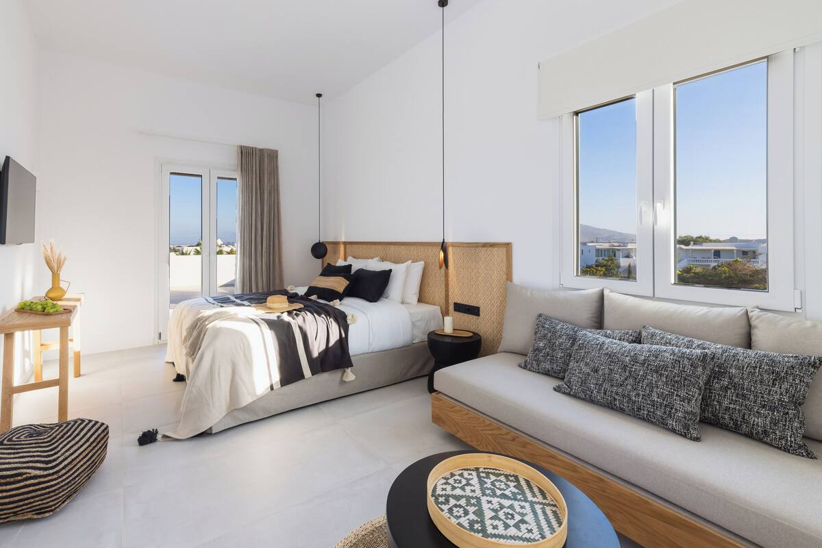 A modern bedroom with a bed, a sofa, and a large window.