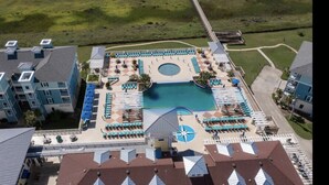 Vue aérienne d’un hôtel doté d’une piscine centrale, de plusieurs espaces de détente et d’une pelouse bien entretenue.