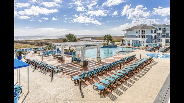 Un complexe hôtelier doté d’une piscine, de chaises longues et offrant une vue sur la plage.