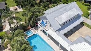 En vy från ovan av en bostadsfastighet med en swimmingpool, solstolar och ett takförsett utomhusområde.