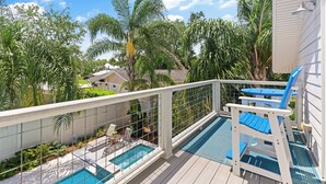 Ett område vid poolen med en pool, ett vitt trädäck och en blå stol.