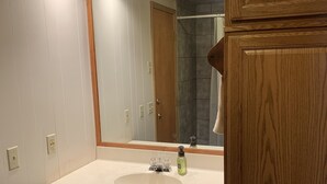 Een badkamer met een houten wastafel, een grote spiegel en een douche.