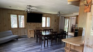 Een houten interieur met een eettafel, stoelen, een bank en een keukenhoek.