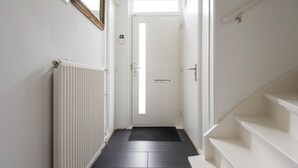 En smal hall med ett element, en dörr längst in och en trappa till höger.