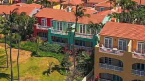 A coastal resort with colorful buildings, palm trees, and a view of the ocean. - Stunning Resort Apartment at Las Casitas (Fajardo)