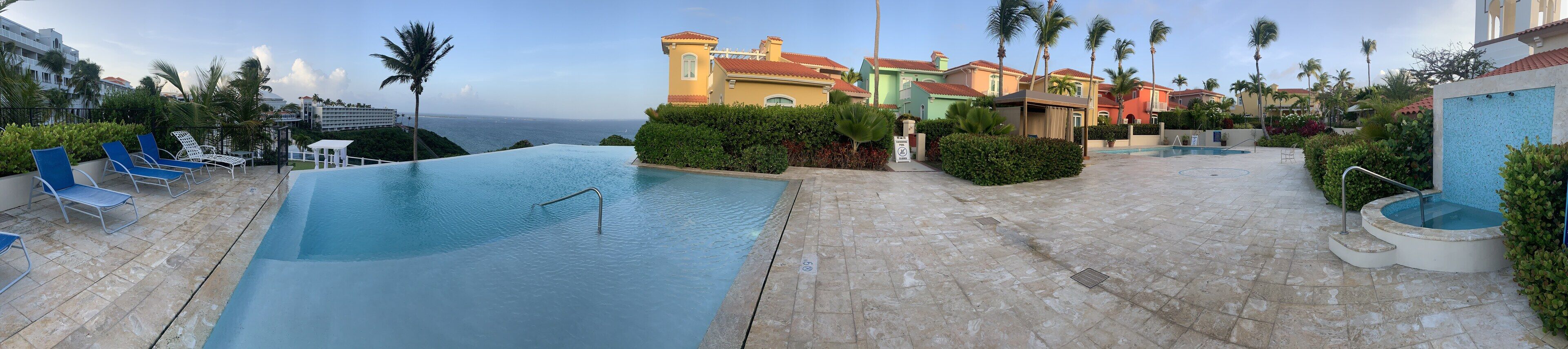 A resort with a large infinity pool, palm trees, and colorful buildings.