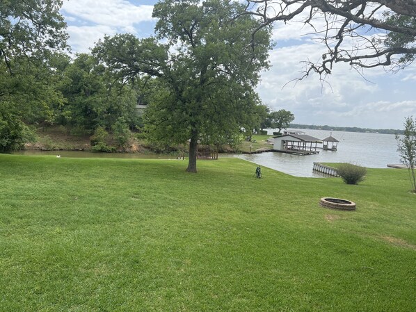 Un espacio cubierto de hierba con un embarcadero y un pabellón junto a un lago.