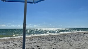 En strandparasol med kig til havet og en sandstrand i baggrunden.