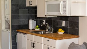 Una cocina compacta equipada con microondas, cafetera y un lavamanos.