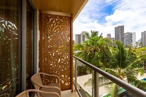 Un balcon offrant une vue sur le paysage urbain, avec des palmiers et un panneau décoratif.