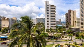 A cityscape with high-rise buildings, palm trees, and a clear sky. - Minutes to Beach | Pool+Gym | WFH Station | Lanai (Honolulu)