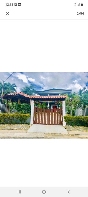 A gated entrance with a red roof and a sign that reads "CASA LOS MADRIDZ".