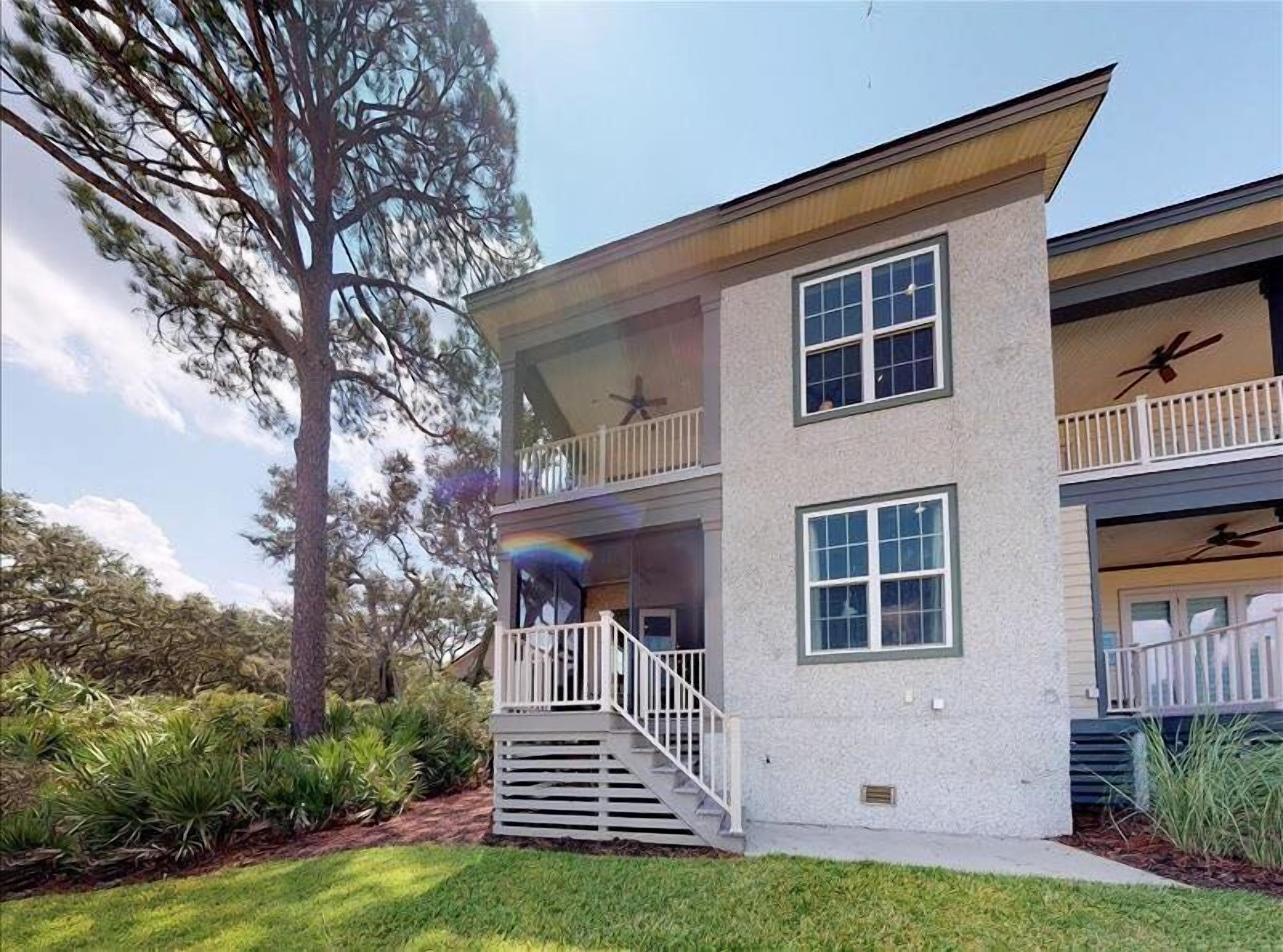 A two-story house with a balcony, a garage, and a tree in the background.