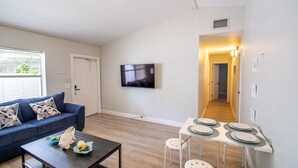 A living room with a sofa, coffee table, TV, and a dining area with a table and chairs. - Beautiful remodeled condo. Steps away from area's top nightlife/1 mi. from beach (Delray Beach)