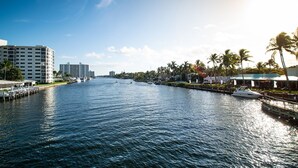 A waterfront view with a marina, palm trees, and buildings along the shore. - Beautiful remodeled condo. Steps away from area's top nightlife/1 mi. from beach (Delray Beach)