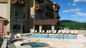 Un hotel con piscina, sillas de descanso y bañera de hidromasaje.