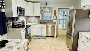 A kitchen with white cabinets, a stainless steel refrigerator, a dishwasher, and a microwave. - Little House in Jasper (Jasper)