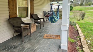 A porch with wicker furniture, a hanging chair, and a doormat. - Little House in Jasper (Jasper)