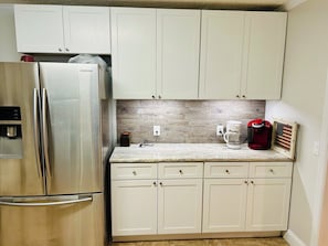 A kitchen with white cabinets, a stainless steel refrigerator, a coffee maker, and a small American flag decoration.