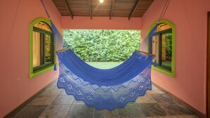 Uma rede pendurada entre duas janelas em arco, com vista para um jardim exuberante.